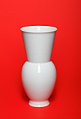 Close-up of white ceramic vase on red background