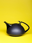 Black teapot on yellow background
