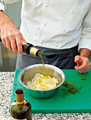 Close-up of adding olive oil to shaved fennel in bowl