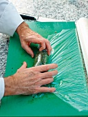 Screw beef being wrapped with cling film on green board