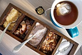 Different types of sugars in wooden box with spoons in it