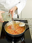Close-up of man's hands pouring liquid from jar in pan