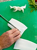 Close-up of man's hands chopping cold leek with knife on cutting board