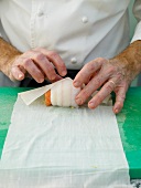 Close-up of man's hands wrapping sole with baking paper