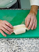 Close-up of man's hands sealing ends of baking paper