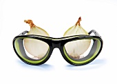 Goggles against two onion on white background