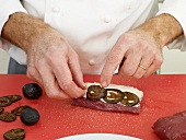 Chef placing slices of pickled vegetable on venison steak