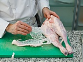 Chef peeling of the skin from lamb's leg