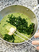 Mixing grind turnip greens in saucepan