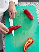 Slitting bell peppers in two halves on cutting board
