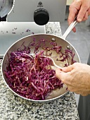 Mixing red cabbage in pan with olive oil and lime juice
