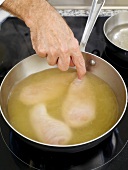 Corn-fed chicken breast pieces dipped in oil in saucepan