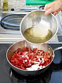Pouring olive oil in chopped red bell pepper and raspberries in pan