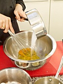 Whisking caster sugar with egg yolk in bowl