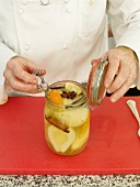 Putting boiled pears with spices in glass jar