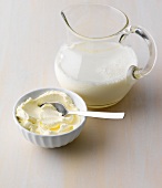 Glass jar of milk and bowl of cream with spoon