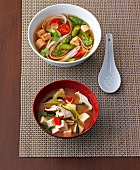 Spicy rice noodle soup and miso soup with tofu in bowls