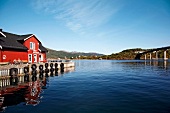 View of wooden red house on pier overlooking fjord in Norway