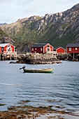 Norwegen, Lofoten, Rote Holzhäuser am Meer, Boot im Vordergrund