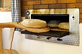 Österreich, Steiermark, Brot wird in einen Ofen geschoben