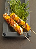 Two mango halloumi kebabs with rocket salad in serving dish