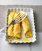 Baked zucchini and ricotta crepes with spatula on baking dish