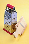 Stainless steel grater and wooden slicer on yellow background