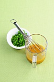 Chives with vinaigrette in glass with wire whisk