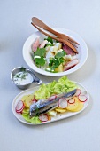 Wasabi potato salad in bowl and pickled herring salad on plate
