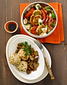 Dumplings with mushrooms on plate and caprese salad in serving dish
