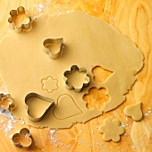 Close-up of dough being cut in various shapes with cookie cutter