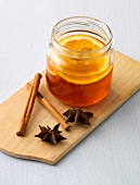 Honey flavoured with orange in jar with cinnamon and anise on cutting board