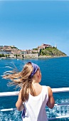 Rear view of woman looking at Portoferraio town from ferry boat in Livorno, Elba, Italy