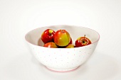 Apples in spotted bowl on white background