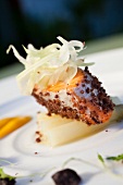 Close-up of salmon trout with olive crust, orange puree and white asparagus