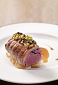 Saddle of lamb in pastry with potato slices on plate