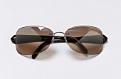 Close-up of ultra-lightweight sunglasses with dark brown ironing on white background