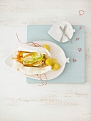 Parchment with cod and vegetable strips on leaf plate