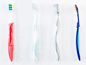 Close-up of four toothbrushes with different colours and shapes on white background