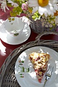 Piece of rhubarb pie on plate with porcelain cup and flowers