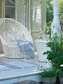 An elegant white wicker chair with a matching table on a summery veranda