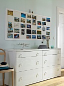 Wall with postcards on white sideboard in living room