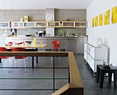 Grosszügige moderne Küche mit Edelstahl-Küchezeile sowie Wandregal und Esstisch aus Ahornholz