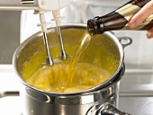 Adding wheat beer and mixing batter in bowl with hand mixer while preparing biersabayon