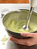 Close-up of mixing pea soup with hand blender in bowl, step 3