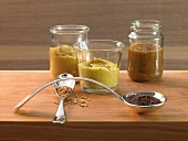 Different types of mustard sauce and mustard seeds on wooden surface