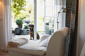 White long chair in living room overlooking dog in terrace garden