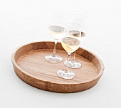 Glasses of wine on round shaped solid oak wooden tray