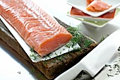Salmon with herbs on wooden board with knife
