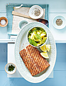 Grilled salmon with warm potato salad, sesame and lemon slice in serving dish